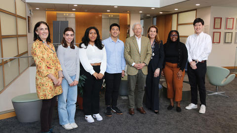 Several Juster Fellow students pose with Kenneth Juster and his wife in a lobby.