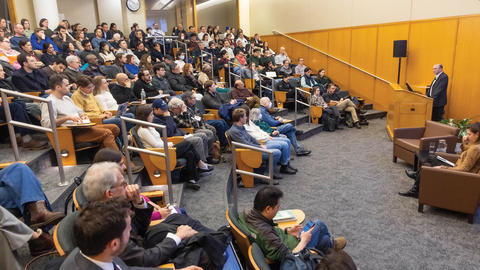 Ben Rhodes stands at lectern and speaks to a packed room in Tsai auditorium.