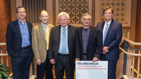Five current and former executive officers, all wearing suits, stand next to each other, and one is holding a Weatherhead Center sign.