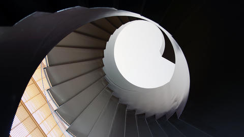 Looking up a spiral staircase in shadows. 