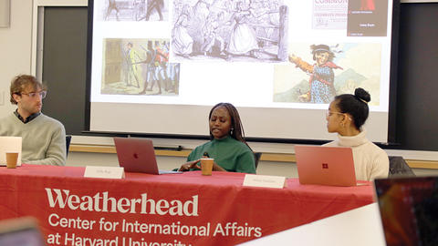 Three students participate in a panel discussion at the undergraduate thesis conference, with a slideshow projected behind them.