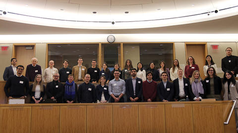 Group of diverse people posing for a photo in a lecture hall.