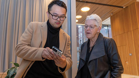A lecture attendee shows Gina McCarthy something on his phone.