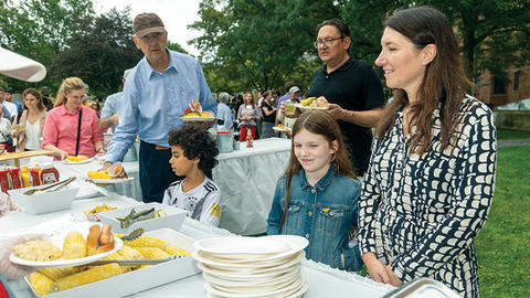 Families stand in line waiting for corn and lobster at the orientation BBQ.