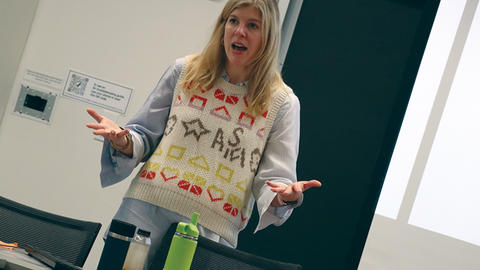 Meg Rithmire stands at the front of the room and presents her research.