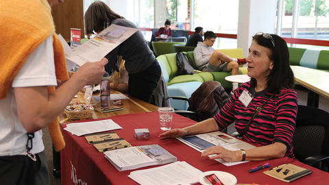 Clare Putnam talks to a student at an informational table.