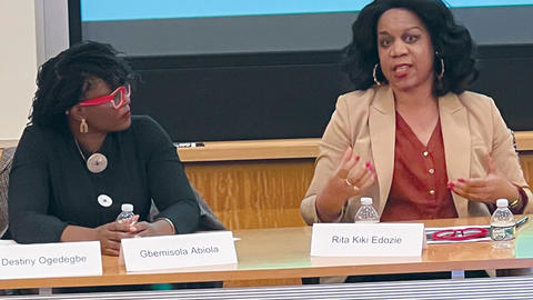 Gbemisola Abiola and Rita Kiki Edozie seated at a table and presenting on the Uganda elections.