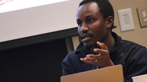 Scholars Program Fellow discusses research in front of his slide show at a Scholars Program seminar
