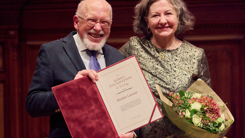 Michele Lamont standing and smiling while holding flowers and receiving the award from another person.