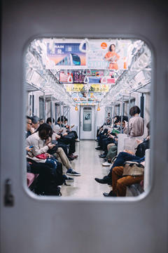 Stock photo of people sitting on the subway looking at their phones in Tokyo, Japan