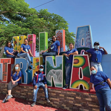 Group of field survey participants sitting on a large sign that says 