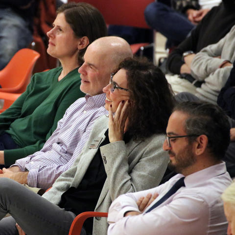 Weatherhead staff sitting in chairs laughing at comedian performing offstage.