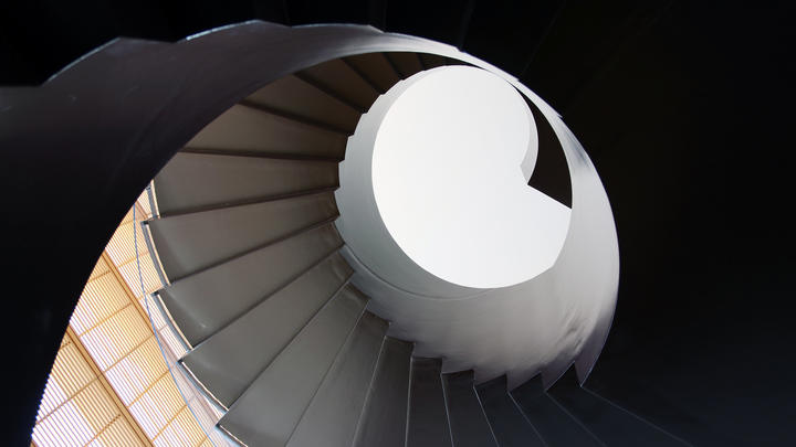 Looking up a spiral staircase in shadows. 