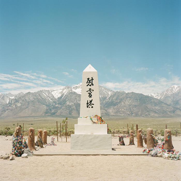 Manzanar Cemetery memorial against a backdrop of large mountains and a blue sky.