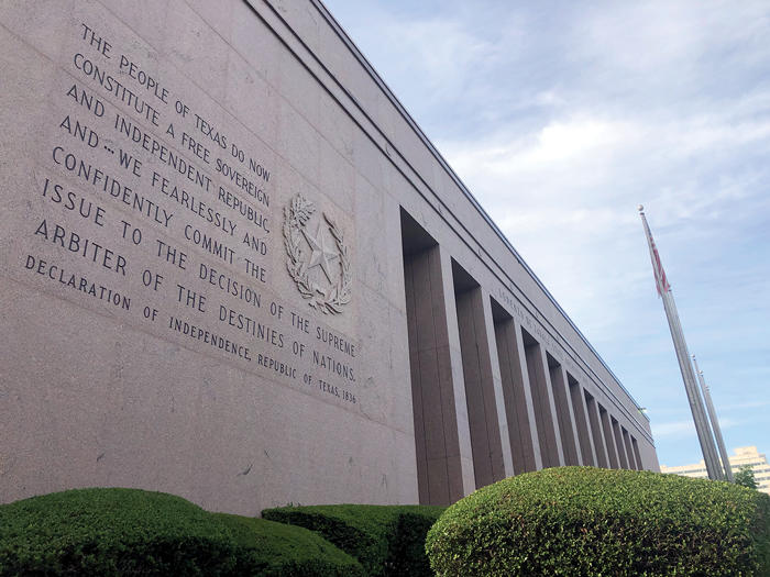The front facade of the Texas State Archives building with a state constitution quote on the building