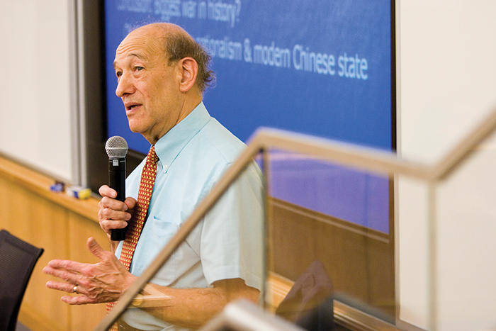 Ezra Vogel giving a talk in a lecture hall against a large computer screen