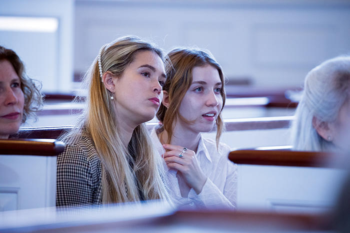 Two young attendees sitting in pews listen to Larry Brilliant's lecture.