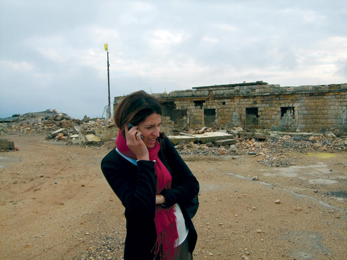 Melani Cammett talks on the phone in front of a crumbling building in Lebanon