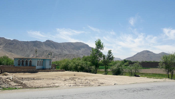 A mosque in a rural area against the mountains in the backdrop