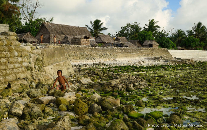 Image of child playing on sea wall at low tide