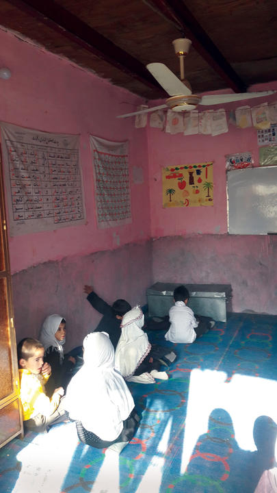 A classroom at the Roshan Street school with several children sitting on the floor talking