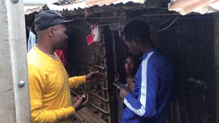 Image of a surveyor asking questions to resident in Mathare