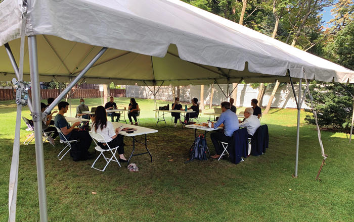 Seminar participants sitting at tables under a white tent outside on the lawn at 61 Kirkland Street