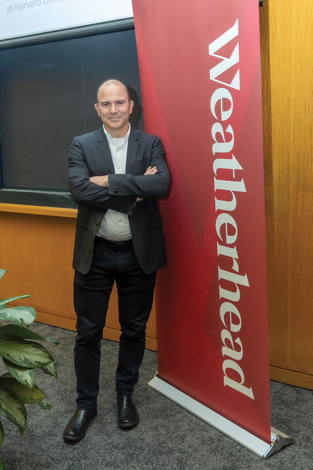 Ben Rhodes stands in front of the blackboard and red Weatherhead banner.