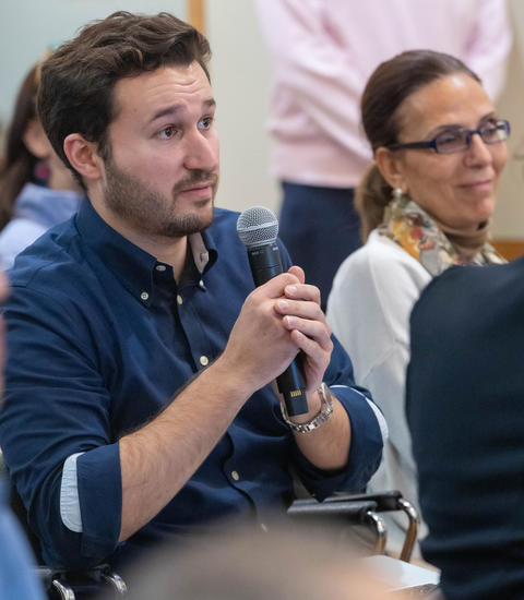 A man holds a microphone and asks a question to the speaker off camera.