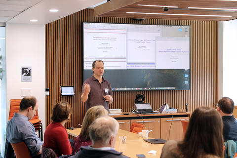 A man stands in a conference room in front of a projection screen.