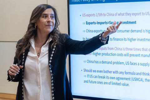 A woman points to a word in her powerpoint presentation.