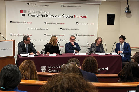 Five panelists are seated behind a table with a red tablecloth and sign behind them that says Center for European Studies at Harvard.