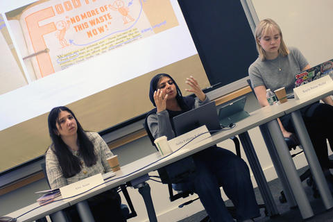 Three panelists—Alin Asim, Aisha Fathima Kakas, and Kayla Renae Reifel—sit at a table during a presentation, with a "Food Front: No More of This Waste Now!" slide projected behind them.