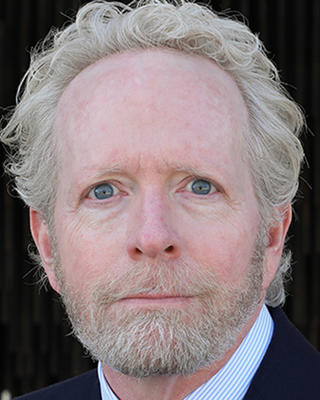 Man with curly white blonde hair looking at camera.