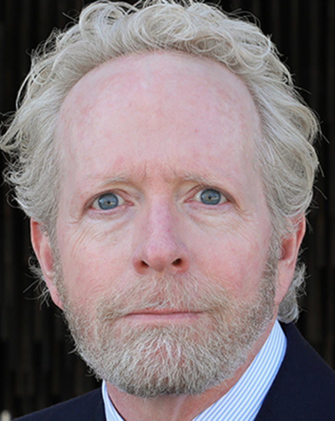 Man with curly white blonde hair looking at camera.