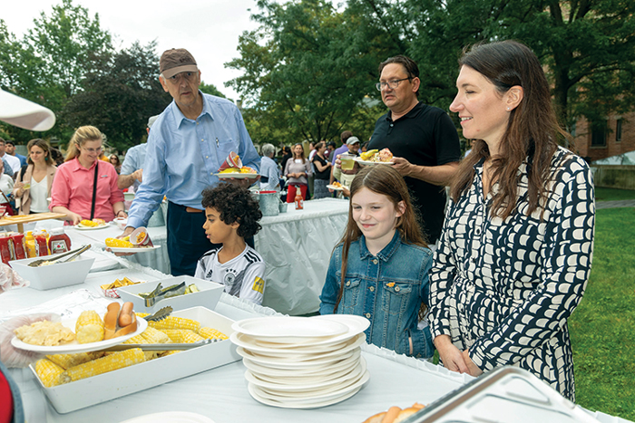 Families stand in line waiting for corn and lobster at the orientation BBQ.