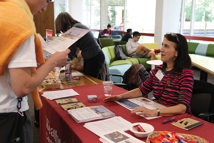 Clare Putnam talks to a student at an informational table.